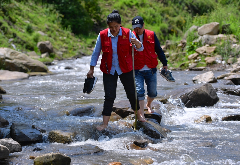 美姑县瓦古乡瓦以村综合帮扶队员涉水开展走访入户。.jpg