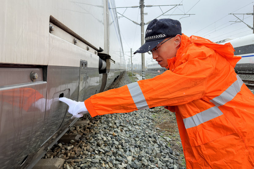 1月24日晨，动车组随车机械师正在雪中对动车组开展出库前车下检查作业（张登登）_副本.jpg