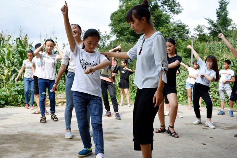 大学生志愿者正在教孩子们跳舞